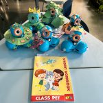 5 Dash robots dressed like animals on a desk with the Class Pet Student Workbook in front.