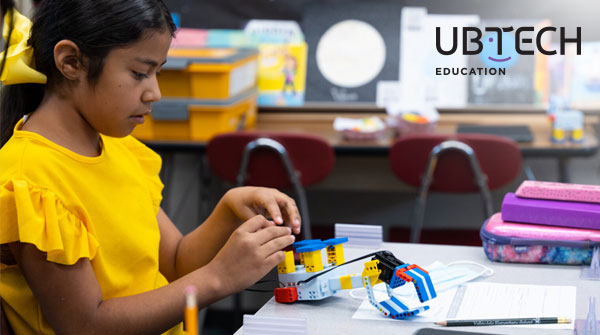 Little boy and teacher pioneering AI in the classroom by playing and building a UBTECH Education robot.