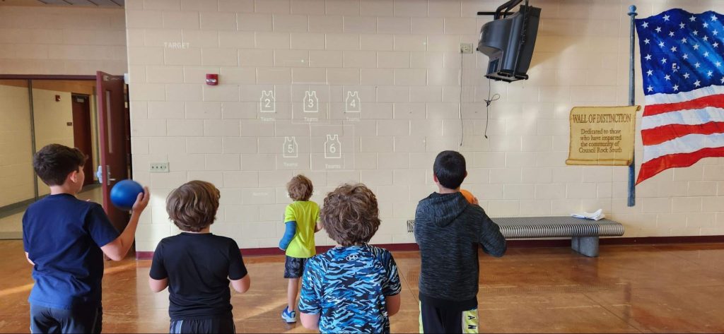 Four young male students staying active with Lü, and throwing balls at the wall.